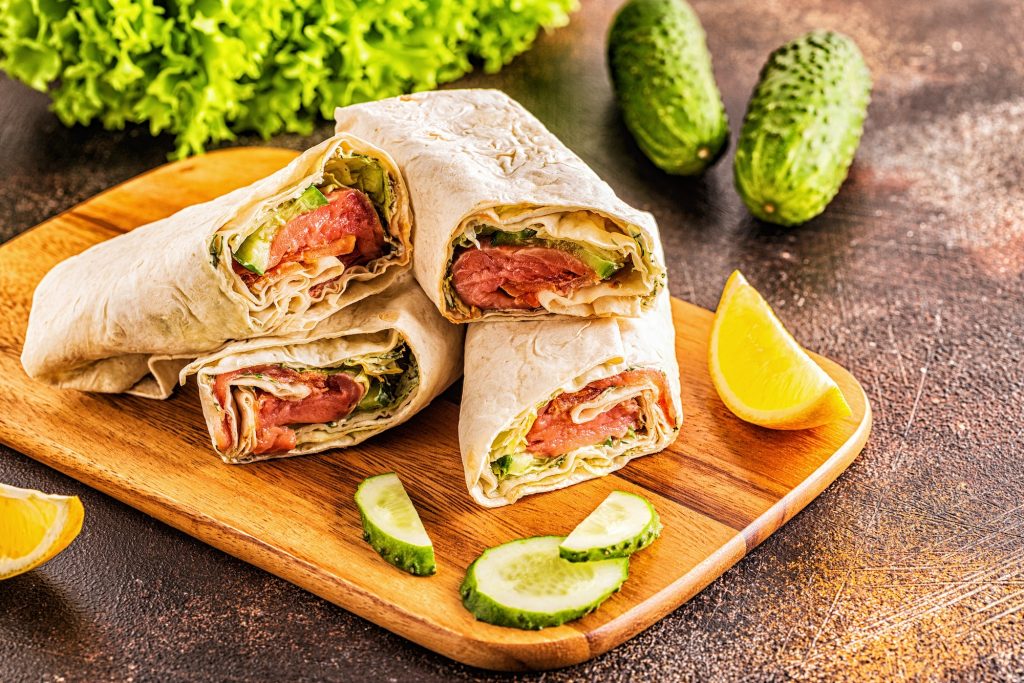Wrapped sandwich with salmon, lettuce, cucumber and cream cheese.