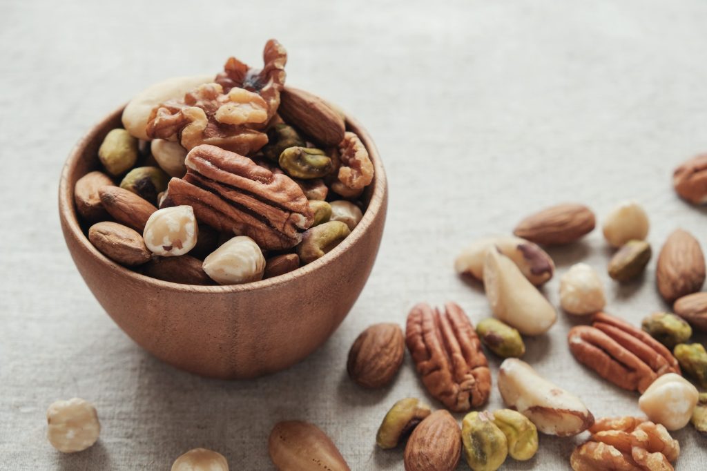 mixed nuts in wooden bowl, healthy fat and protein food and snack